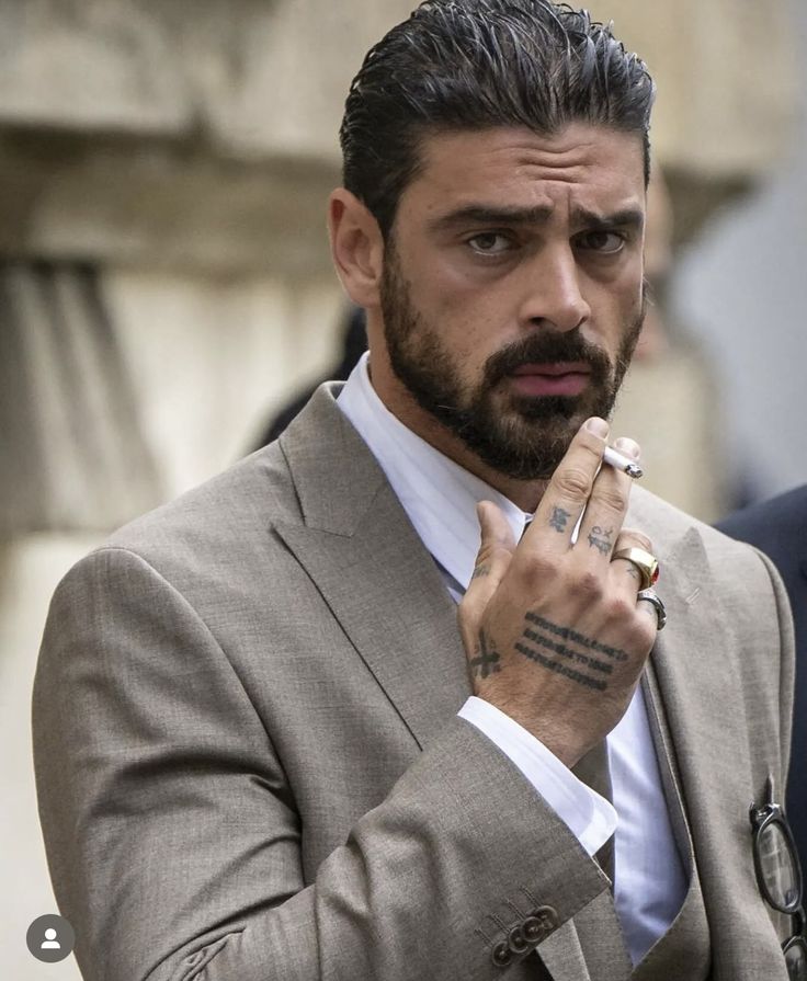 a man in a suit and tie with tattoos on his hand