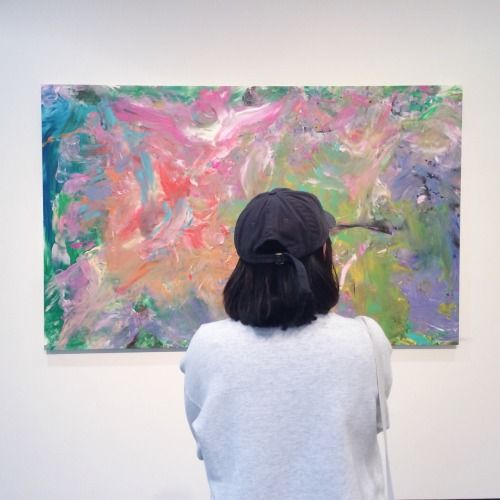 a woman looking at an abstract painting on display