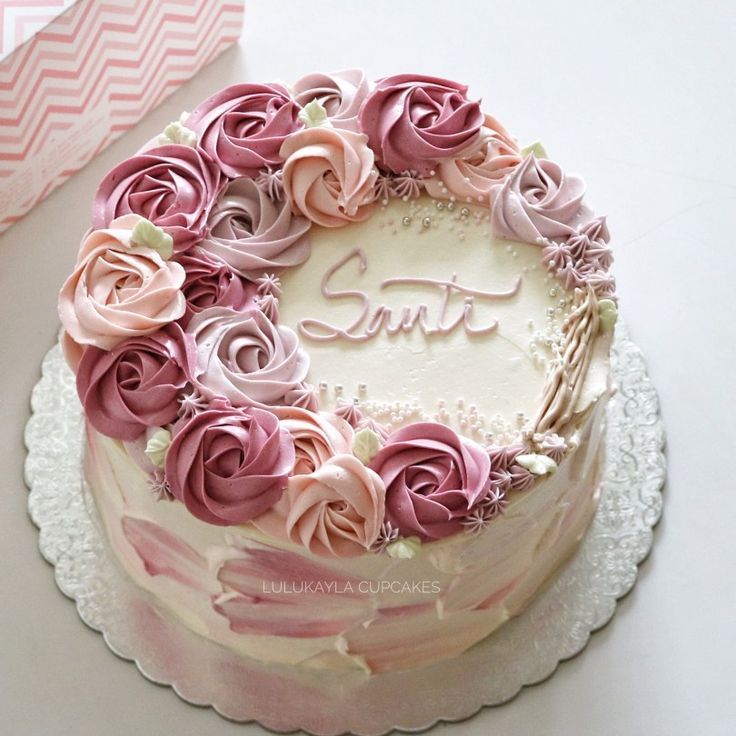 a cake decorated with pink and white flowers on a plate next to a box that says love