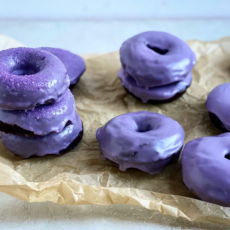 purple doughnuts are sitting on top of brown paper