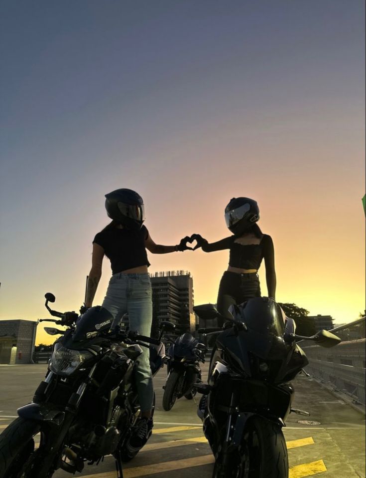 two women standing next to each other on motorcycles