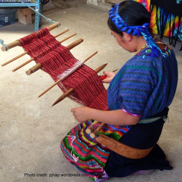 a woman sitting on the floor working on some kind of weaving project in her shop