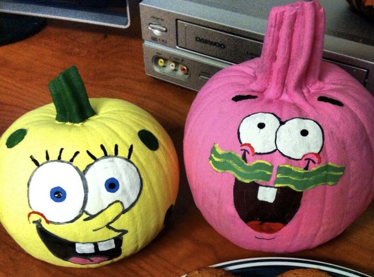 two decorated pumpkins sitting on top of a wooden table