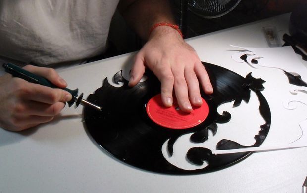 a person using a pair of scissors to cut out a vinyl record