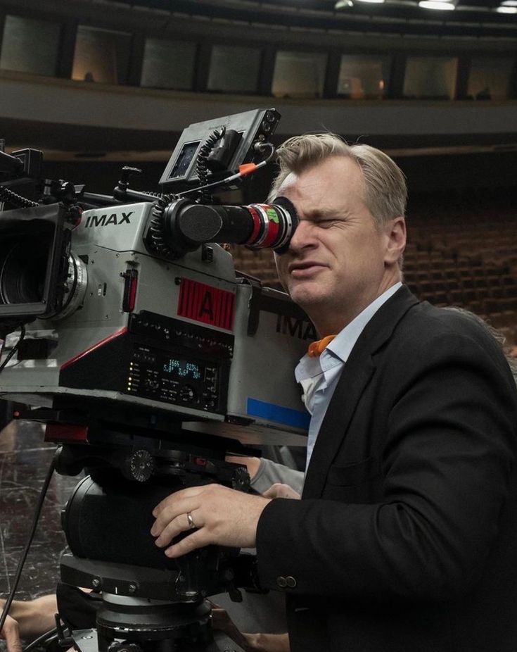 a man standing next to a camera on top of a tripod