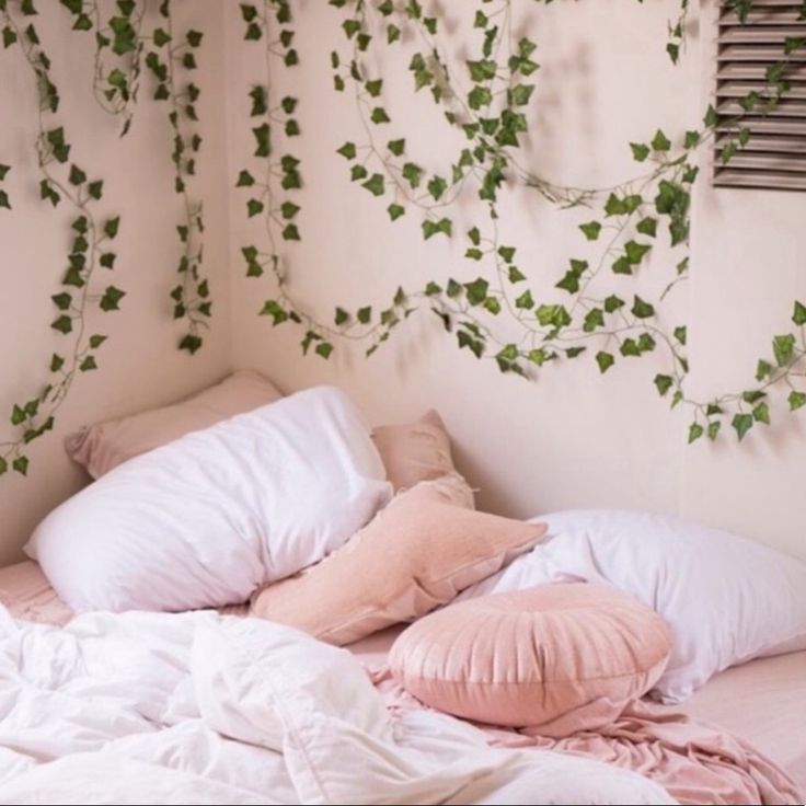 an unmade bed with pink pillows and ivy on the wall next to it that says live mini loop