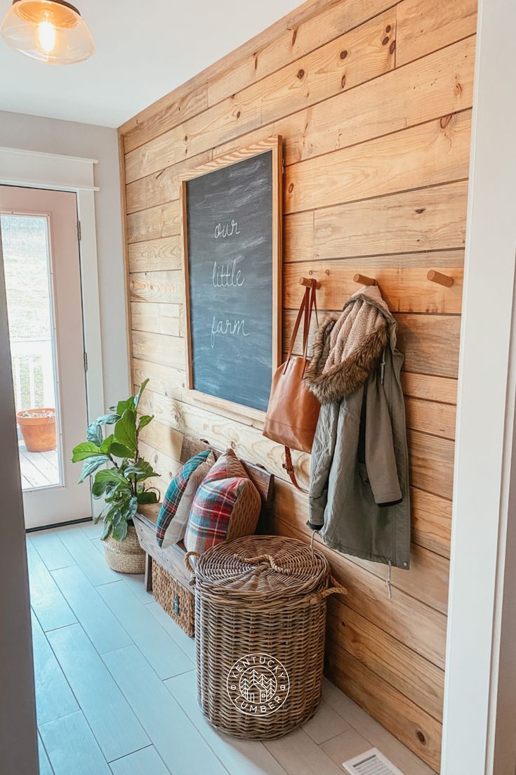 a wooden wall with a chalkboard and coat hanging on it's side next to a wicker basket