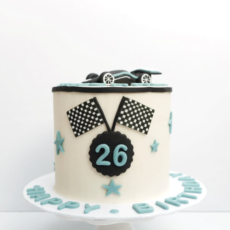 a birthday cake decorated with cars and stars on a white tableclothed stand,