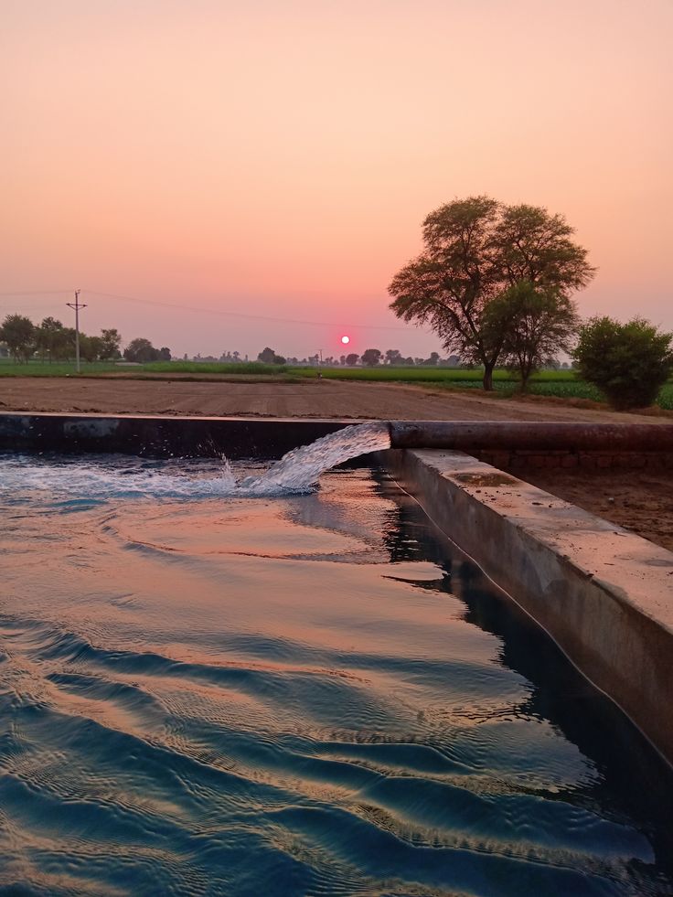 the sun is setting over an open water channel