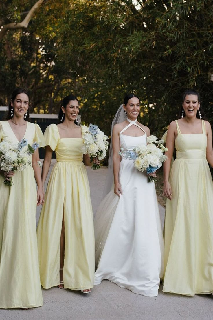 four bridesmaids in yellow dresses are posing for a photo with their bouquets