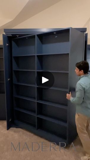 a man standing in front of a bookcase with his hand on the open door