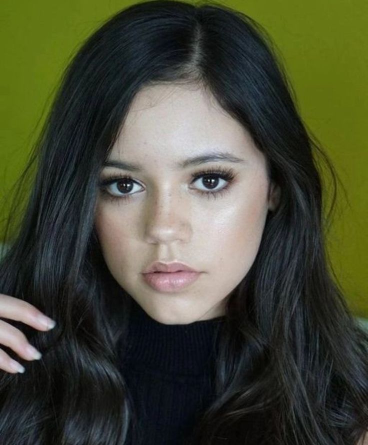 a woman with long black hair and blue eyes wearing a turtle neck sweater looking at the camera