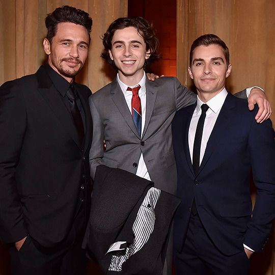 three men in suits posing for the camera