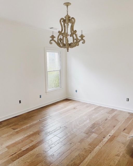 an empty room with hard wood floors and a chandelier