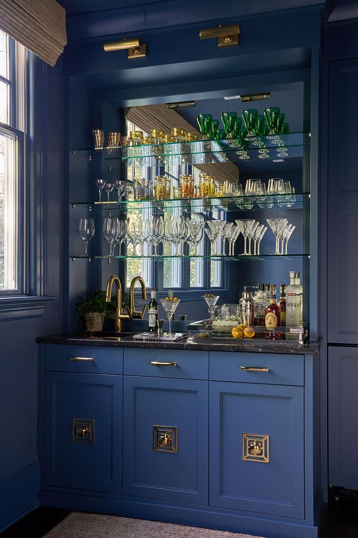 a blue bar with lots of wine glasses and bottles on it's glass shelves