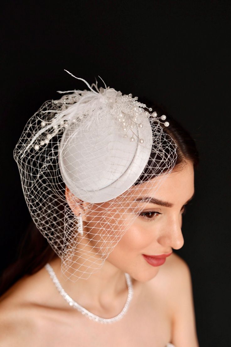 a woman wearing a white veil and headpiece with pearls on the top of it