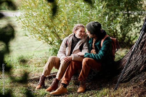 two people sitting next to each other near a tree