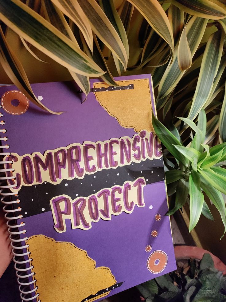 a purple notebook with the words ombreensive project written on it next to a potted plant