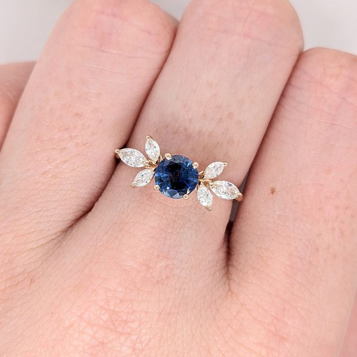 a woman's hand with a blue and white diamond ring on top of it