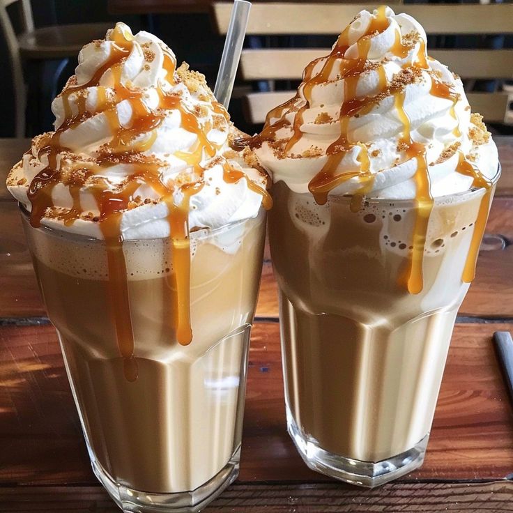 two glasses filled with ice cream and caramel toppings on top of a wooden table