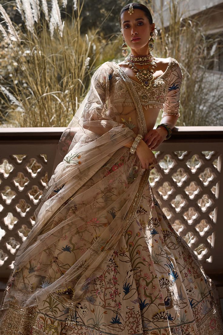 The shikargah lehenga in ivory silk, adorned with multi-colored resham aari, hand-embroidered sequins, silver dabka, and mirror work. This exquisite piece tells a tale of flora and fauna, capturing the vibrant beauty of nature. Paired with a net dupatta, it's a wearable canvas of intricate artistry, making every step a poetic journey through an enchanted forest. Wedding Dresses Indian, Indian Wedding Outfit, Bridal Lehenga Collection, Indian Photoshoot, Indian Dresses Traditional, Ethnic Looks, Indian Inspired, Party Wear Indian Dresses, Ivory Silk