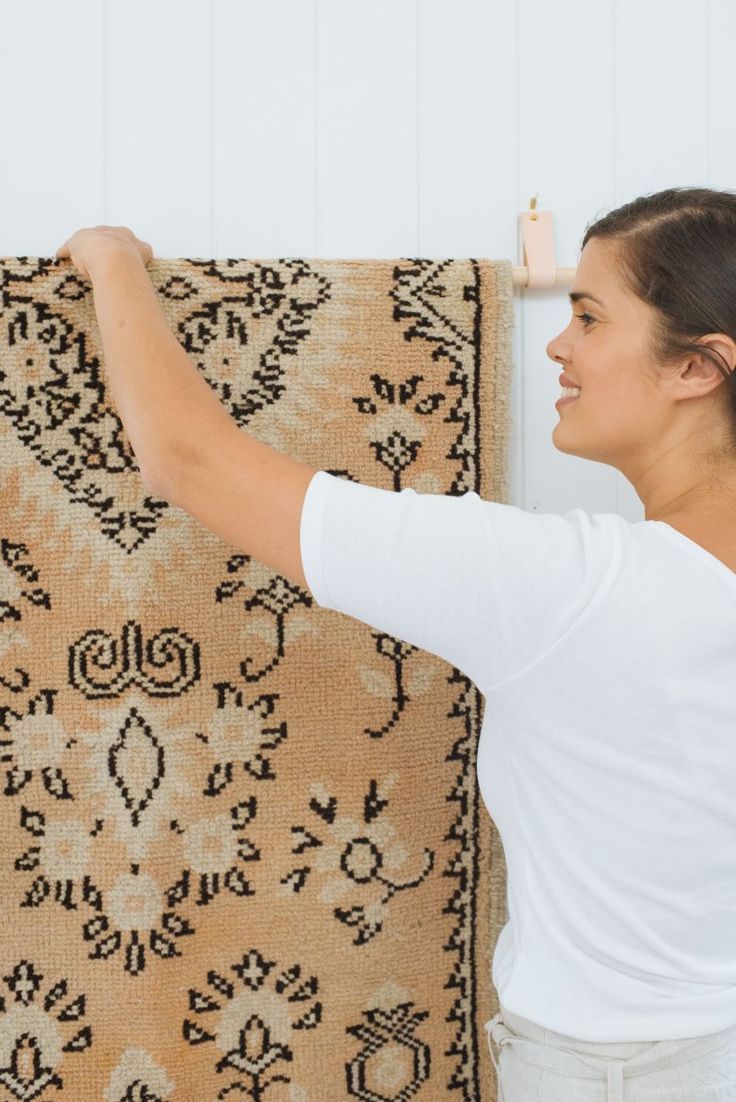 a woman is placing rugs on the wall