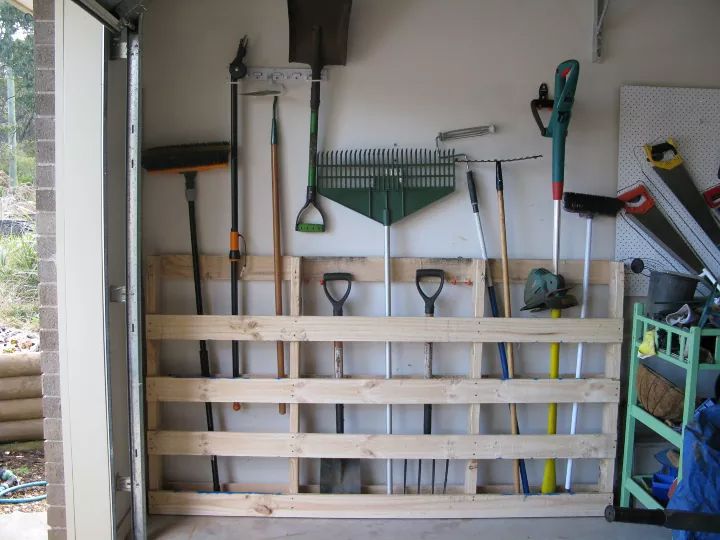 a garage filled with lots of tools and hanging on the wall next to a door