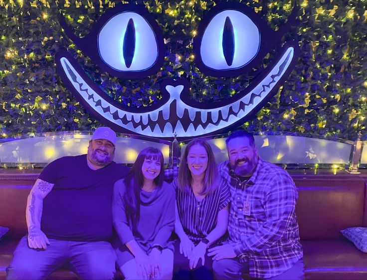 three people are sitting on a couch in front of a fake smiling face at night