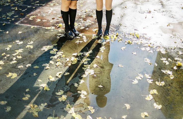 two girls are standing in the rain with umbrellas