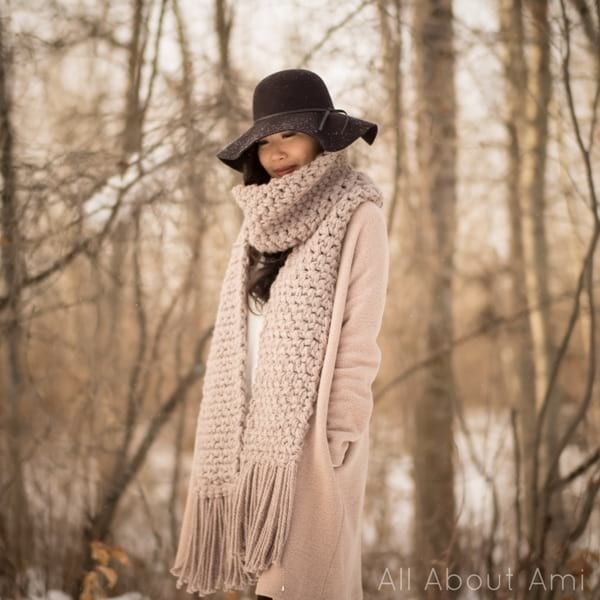 a woman standing in the snow wearing a hat and scarf