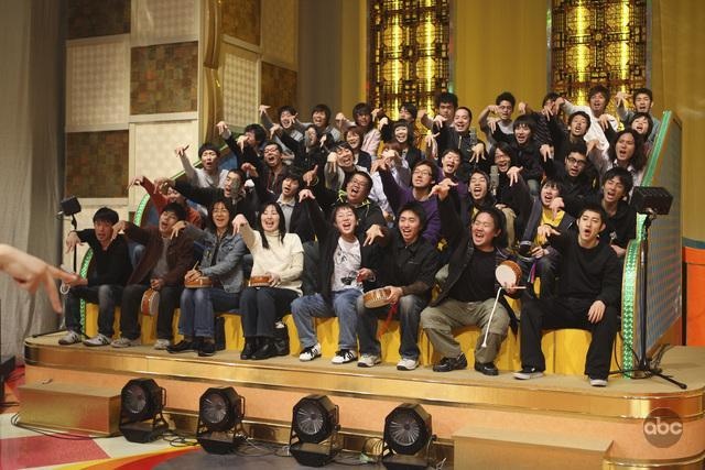 a group of people sitting on top of a stage with their hands in the air