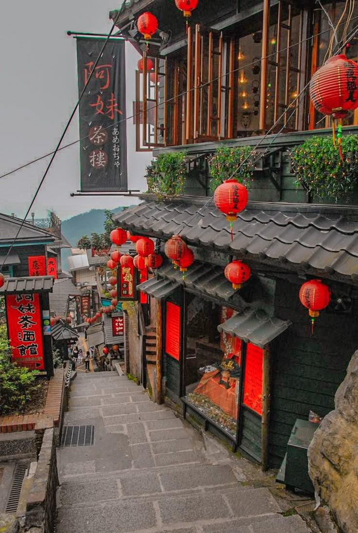 an alley way with red lanterns hanging from the roof and stone steps leading up to it