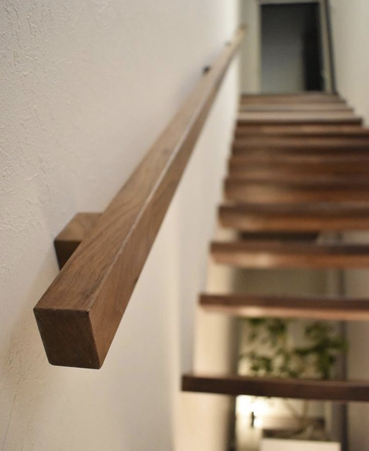 a wooden stair case next to a white wall