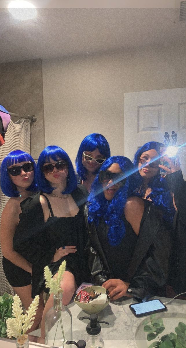 a group of women with blue hair are posing in front of a mirror