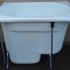 a large white sink sitting on top of a metal stand in front of a wall