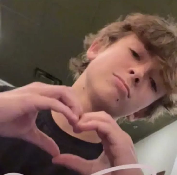 a young man making a heart with his hands