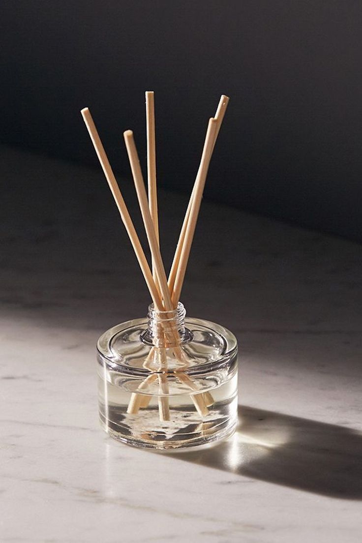 a glass jar with reeds in it on a table