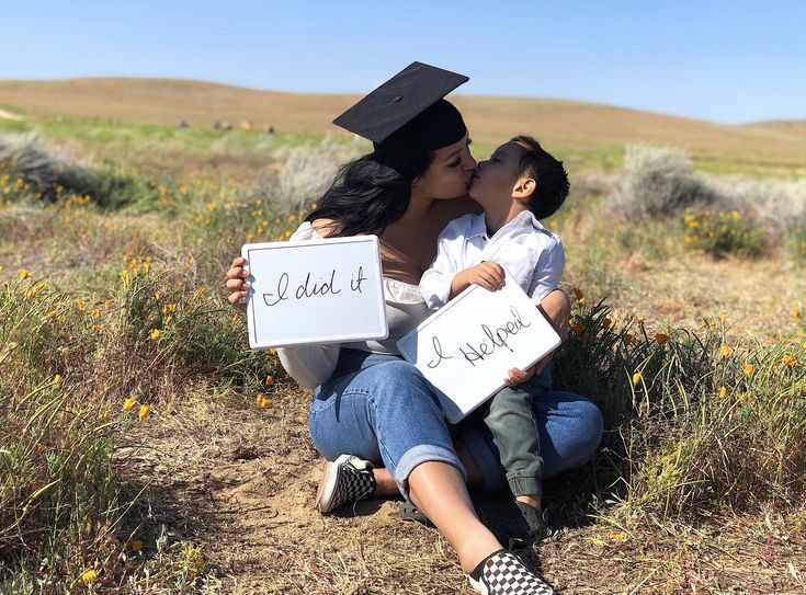 a woman holding a child and kissing her on the cheek while wearing a graduation cap