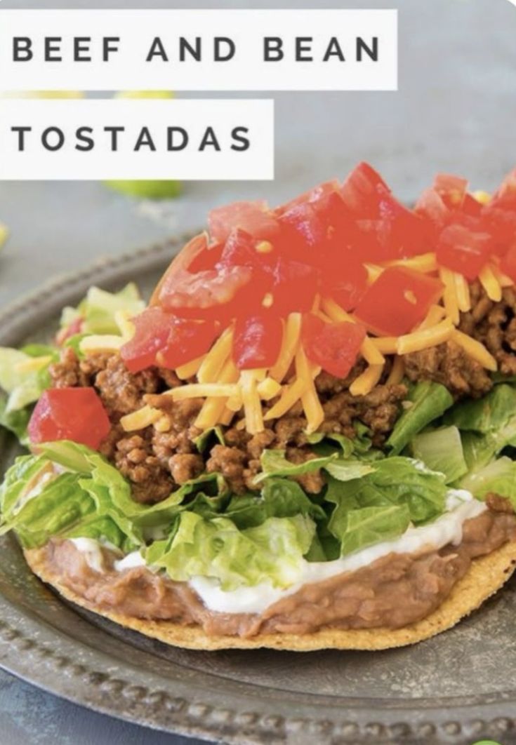 a taco with lettuce, tomatoes and cheese on it sitting on a plate