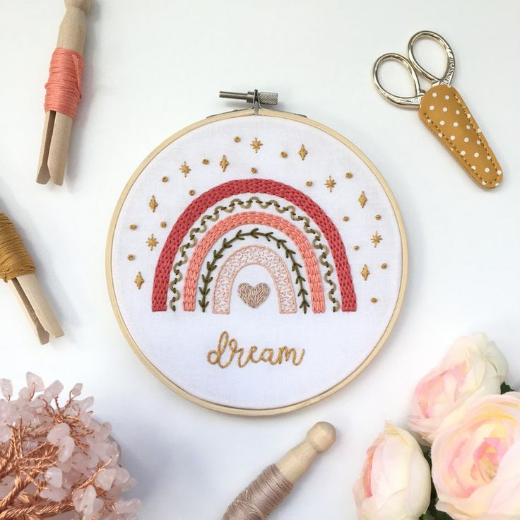 a cross stitch pattern with the word dream and a rainbow on it next to some craft supplies