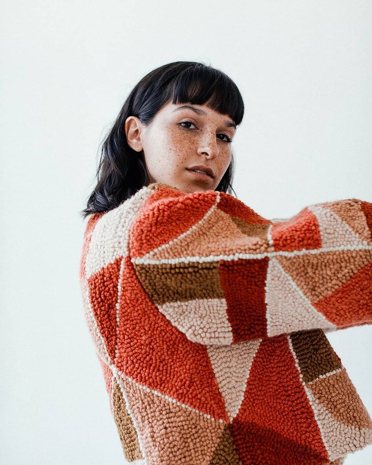 a woman is wearing a sweater made out of knitted material and posing for the camera