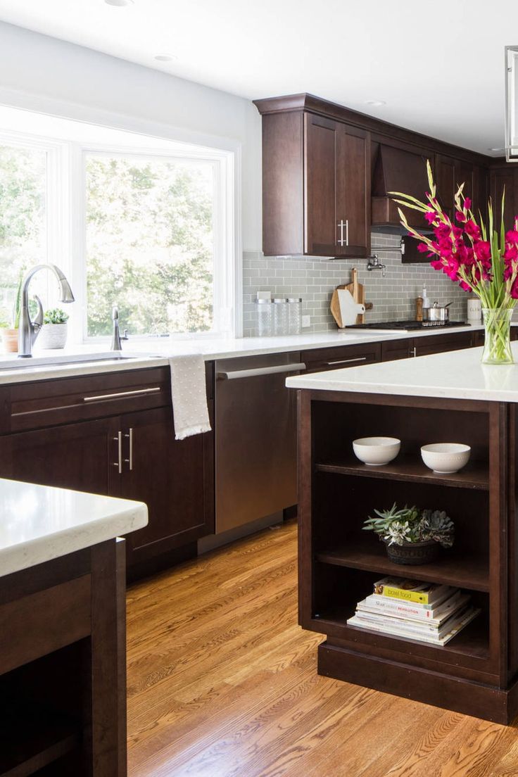 a kitchen with wooden floors and white counter tops, dark wood cabinets, and open shelving