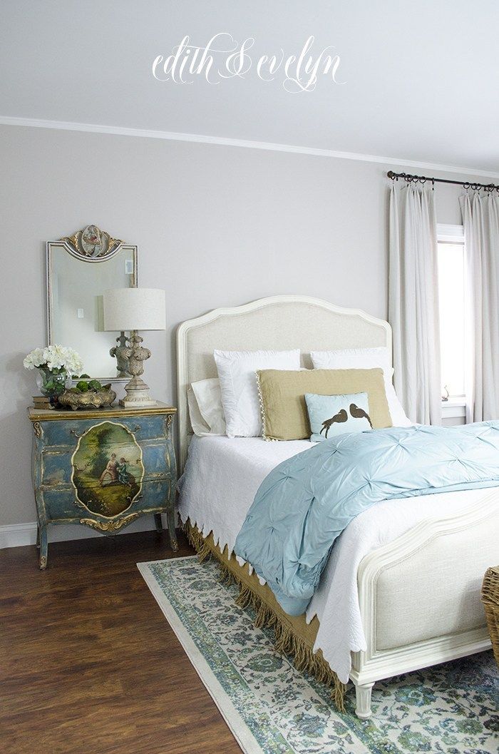 a white bed sitting next to a window in a bedroom on top of a hard wood floor