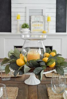 the centerpiece is decorated with lemons and greenery on top of a wooden table