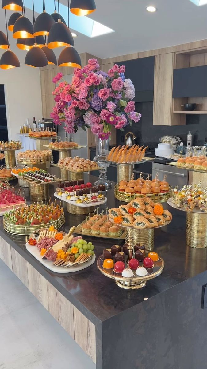 a table filled with lots of food on top of a black counter next to lights