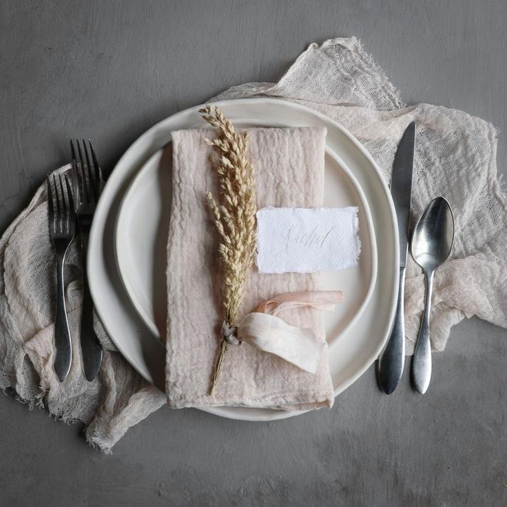 a white plate topped with a piece of paper next to two forks and spoons