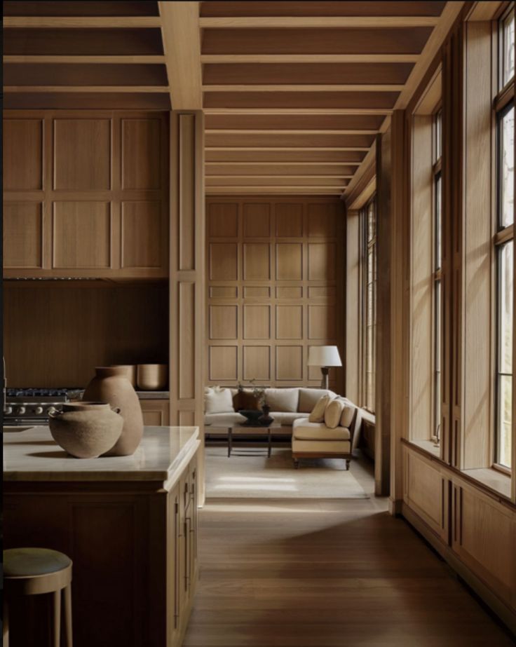 a living room filled with lots of furniture and wood paneling on top of a hard wood floor