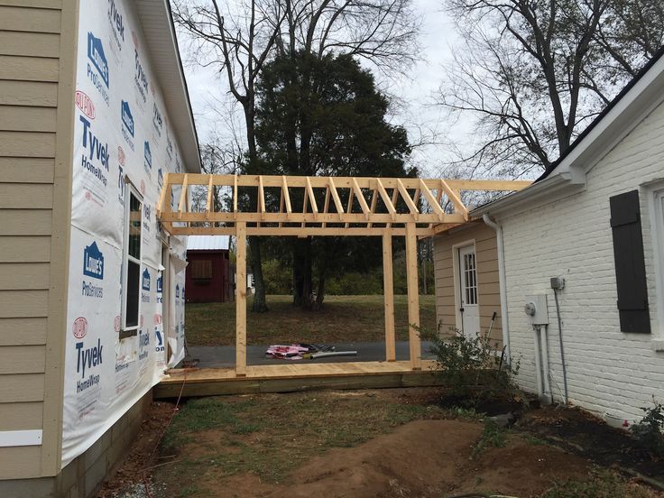 a house being built in the middle of a yard with wood framing and siding on it