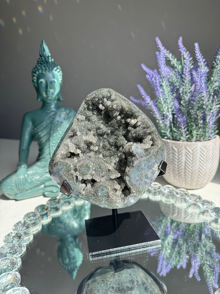 a glass table topped with a statue next to a potted plant