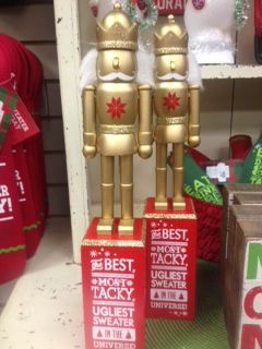 two gold robot figurines sitting on top of boxes in front of christmas sweaters